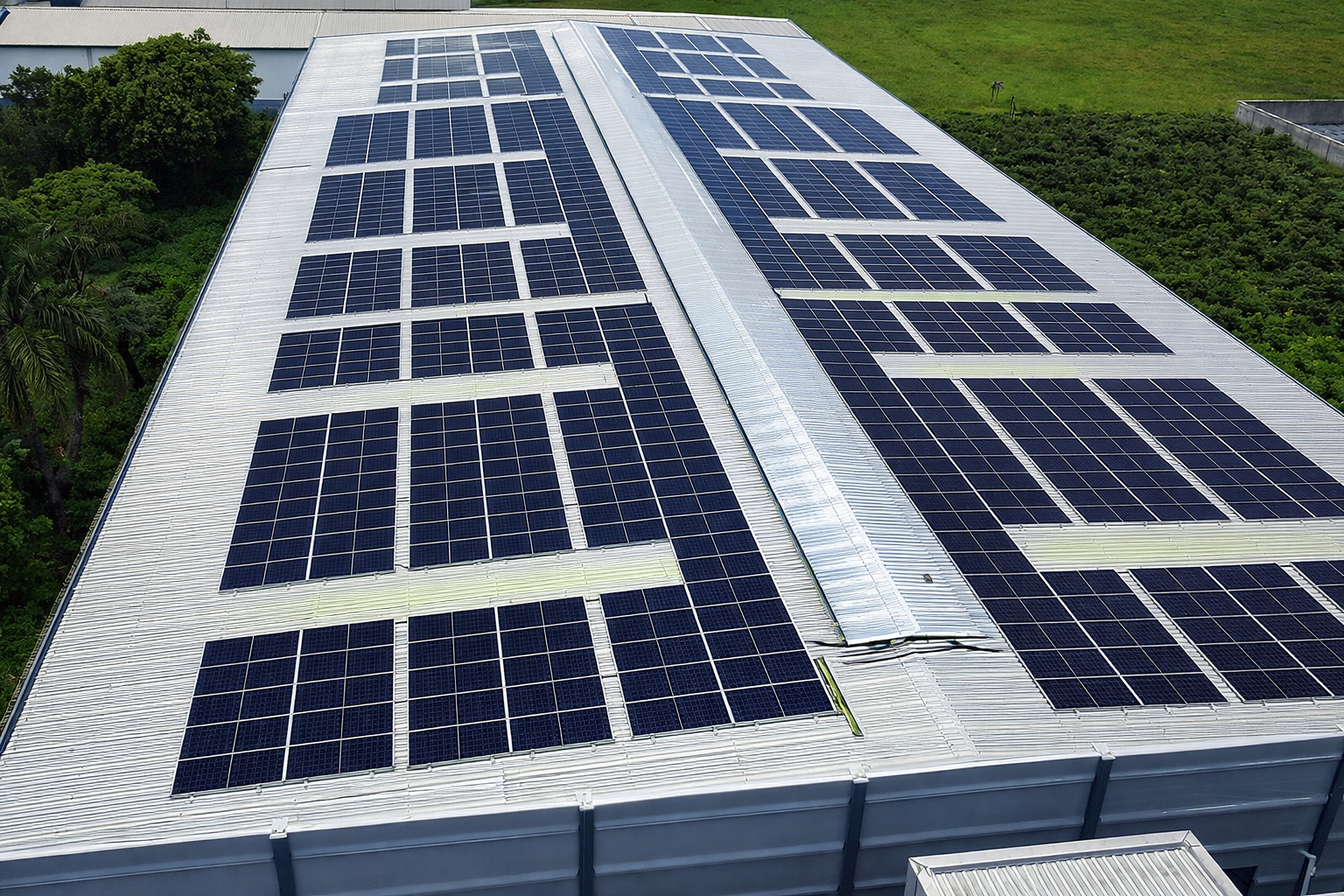 Usina solar fotovoltaica instalada em telhado metálico industrial, vista aérea